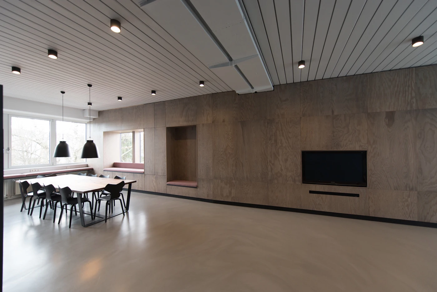 Grande salle de travail moderne en béton et bois, sans personne.