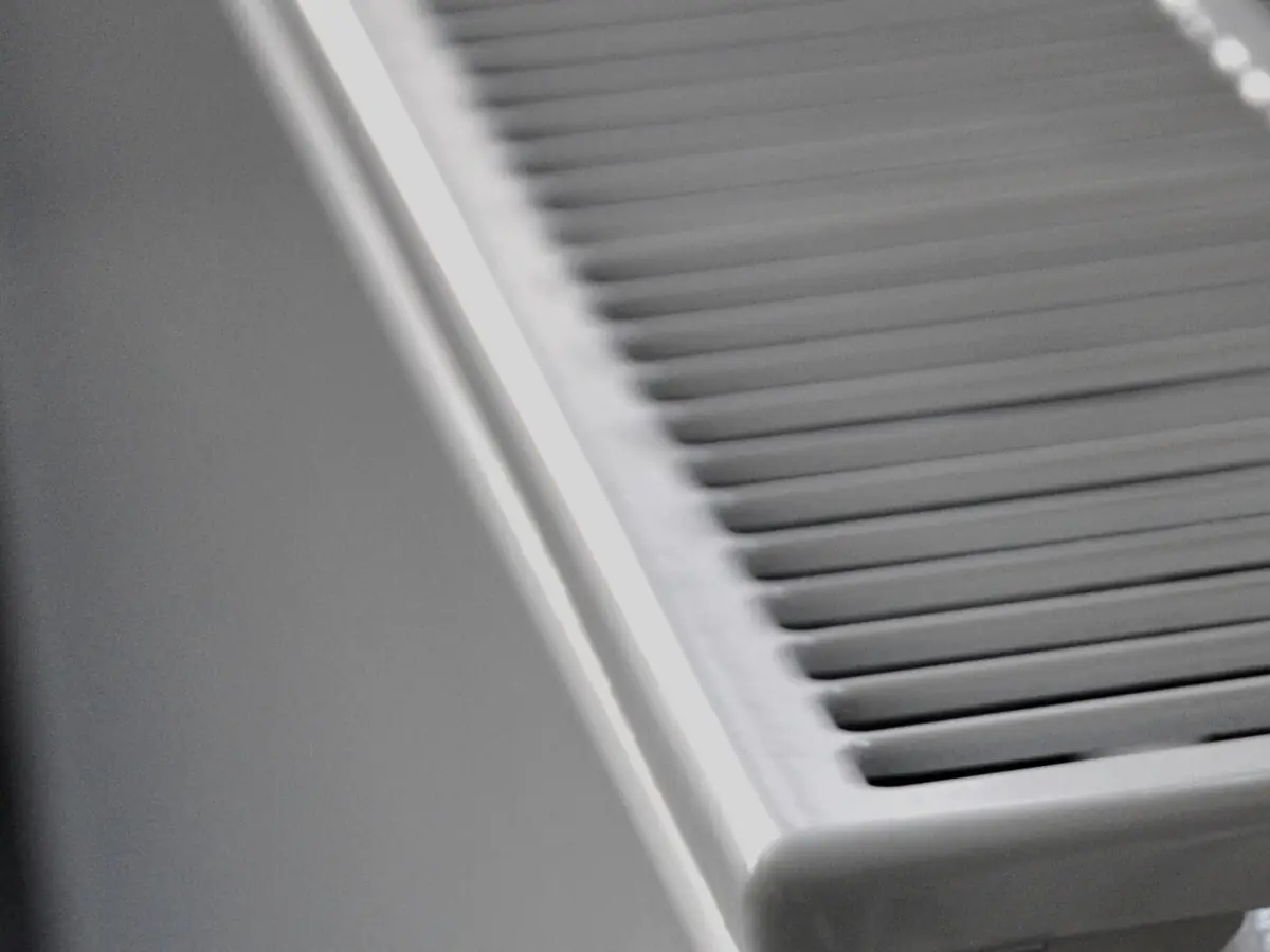 Ailettes d'un radiateur en acier vues de très près, en lumière rasante.