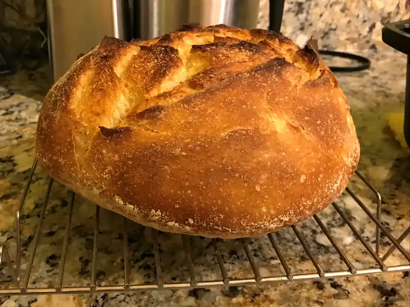 Une grosse miche dorée qui refroidit sur une grille métallique.
