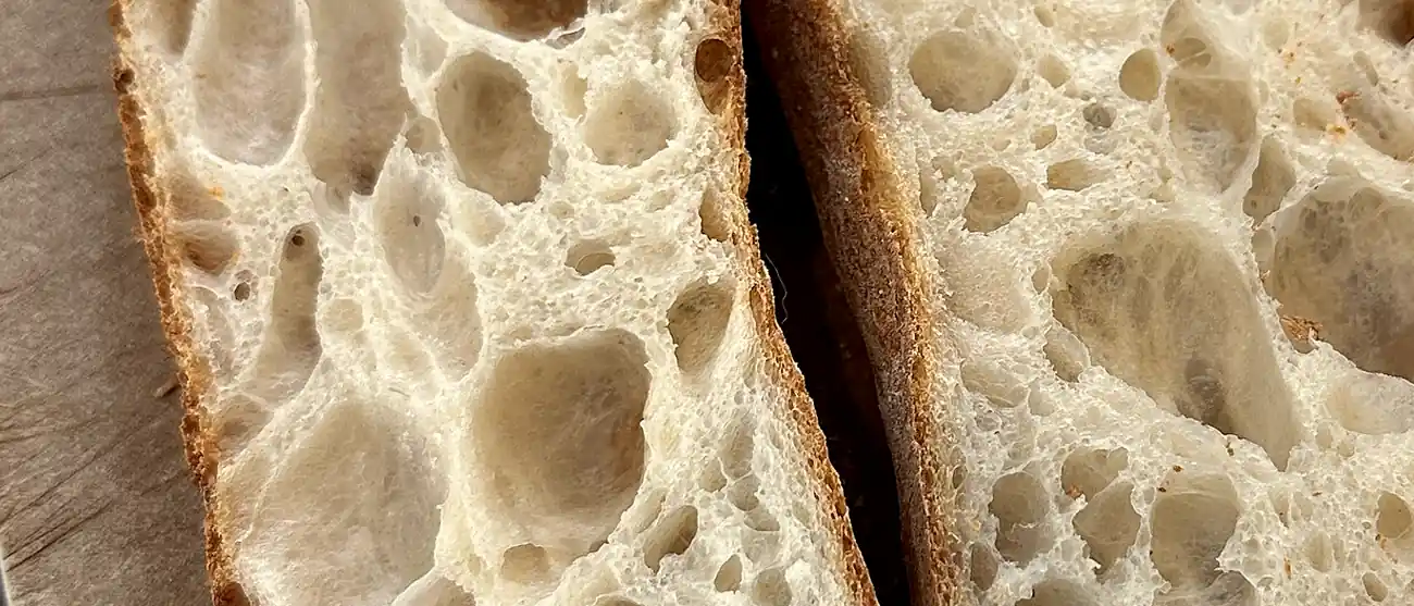 Gros plan sur une baguette ouverte en deux, la mie très alvéolée et la croûte fine.