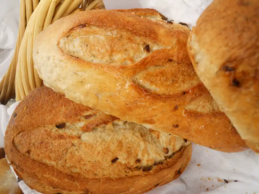 Trois gros pains rustiques bien dorés, entassés dans un panier en osier.
